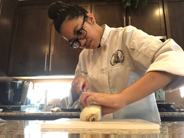 Intently+measuring+with+her+eyes%2C+sophomore+Jayden+Licanto+makes+precise+cuts+in+her+onion%2C+as+part+of+her+knife+skills+lab.+Home+labs+allow+students+to+experience+hands-on+learning+in+a+virtual+classroom+during+the+pandemic+when+physical+teaching+is+impossible.+With+everything+thats+been+going+on%2C+school+has+been+really+challenging%2C+but+I+think+doing+at+home+labs+is+actually+a+good+opportunity+for+culinary+students%2C+Licanto+said.+For+me%2C+freshman+year+was+kind+of+stressful+because+I+didnt+really+know+where+anything+was+in+the+kitchens.+Now%2C+Im+in+my+own+kitchen%2C+and+I+have+the+luxury+to+redo+a+lab+or+take+more+time+on+it+if+Im+confused.+Photo+Credit%3A+Jayden+Licanto