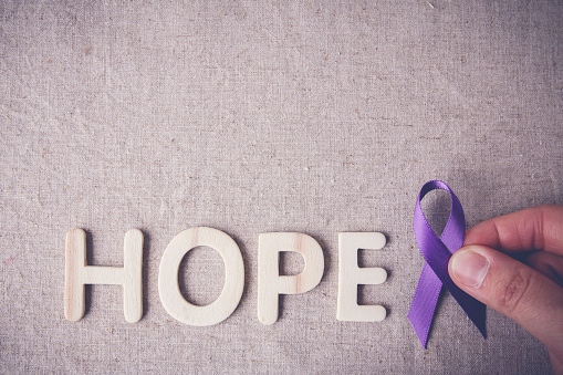 fingers holding Purple ribbon with HOPE wooden letter, toning, A