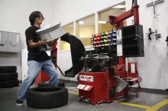 Junior Alvin Claro lifts the rim of a tire. The Auto-Tech program teaches students how to apply useful skills to fix up cars. 
