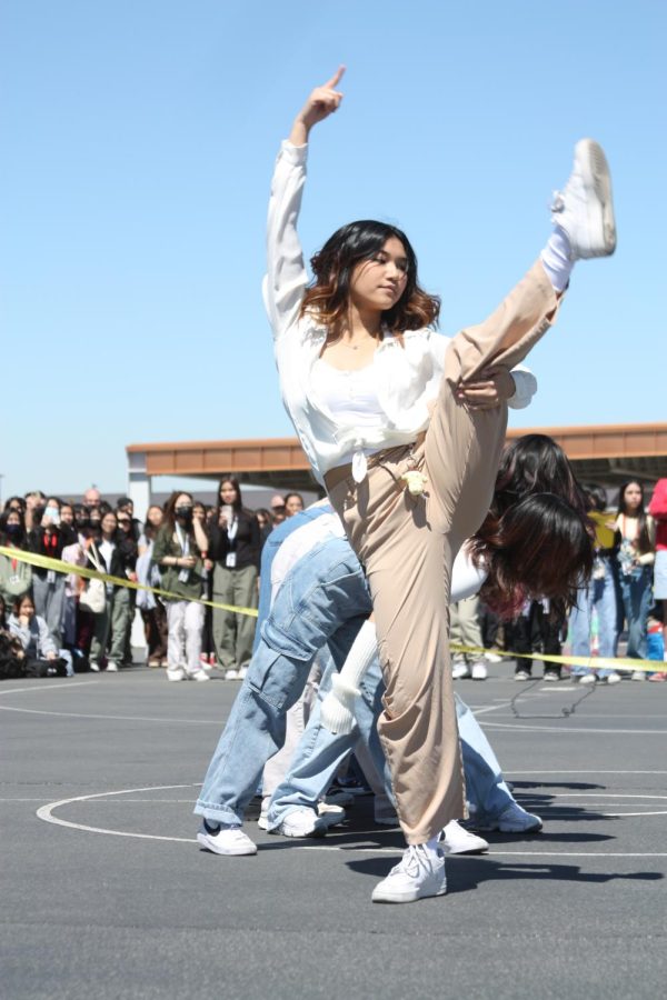 Holding her leg up, junior Danika Molina does a choreographed dance with the rest of K-pop club to entertain those in the audience at the assembly.