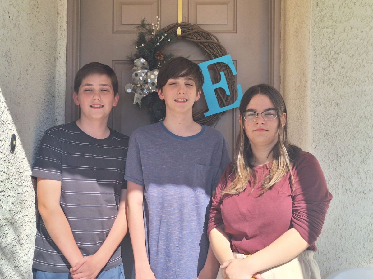Posing together for a picture in front of their childhood home. The Evarts triplets share a lot more than just their identical features. “Growing up we had to share a lot of stuff,” freshman Emily Evarts said. “and even now I borrow some of my brother’s clothes, and they borrow some of my drawing or art supplies. But that is the nice thing about being a triplet.” 
