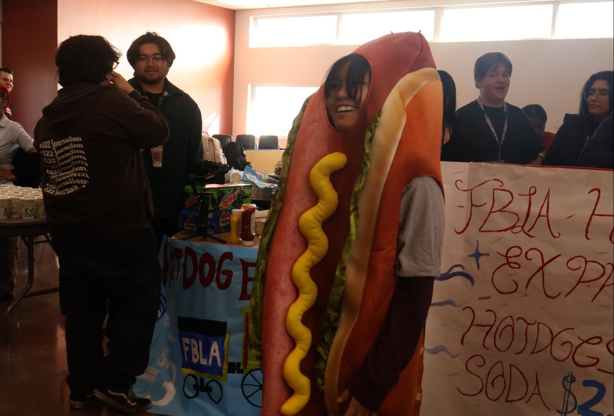 Attracting customers, FBLA Parliamentarian Arcade Encarnacion advertises the club’s hotdog stand at Winterfest. The club sold hotdogs and soda, making around $70 total. “Our club president decided to borrow a costume from her friend, and I was appointed as the hotdog mascot,” Encarnacion said. “It was kind of slow, but then I had this wonderful idea of going up to people and saying that I would dance for them if they bought a hotdog from our stand.” 