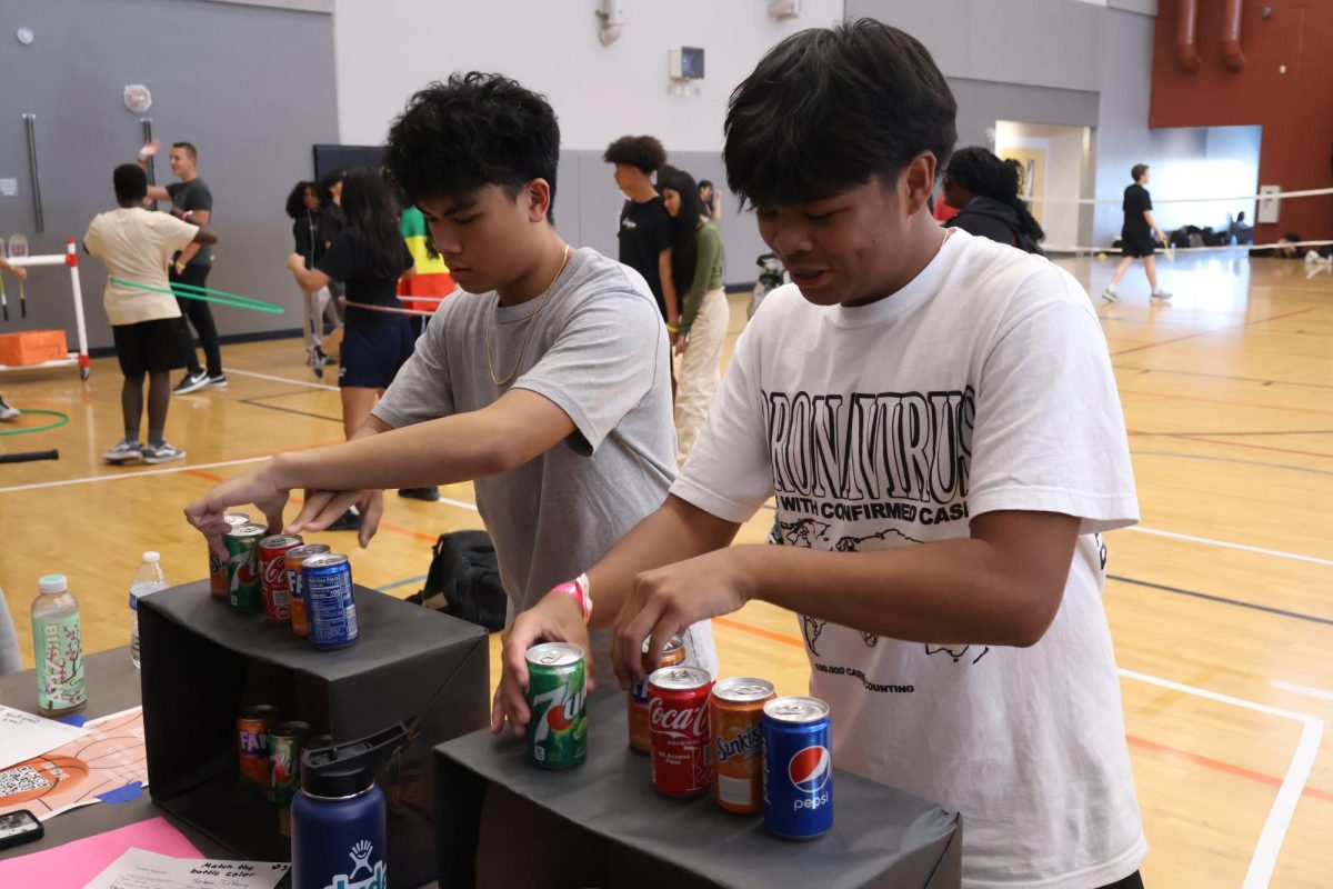 Switching around cans, senior Riley Longboy attempts to match the order of the soda above the box with the soda inside the box to earn bonus points for his team.
