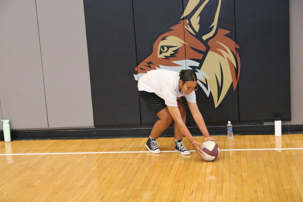 Following drills where students practiced bumping the ball, freshman Gracie Johnson picks up a volleyball that was sent out of bounds. Teams refined their teamwork with volley circles before competing. “I’ve actually never played volleyball before,” Johnson said. “My favorite part about this game is working with my teammates and bonding with them during practice.”