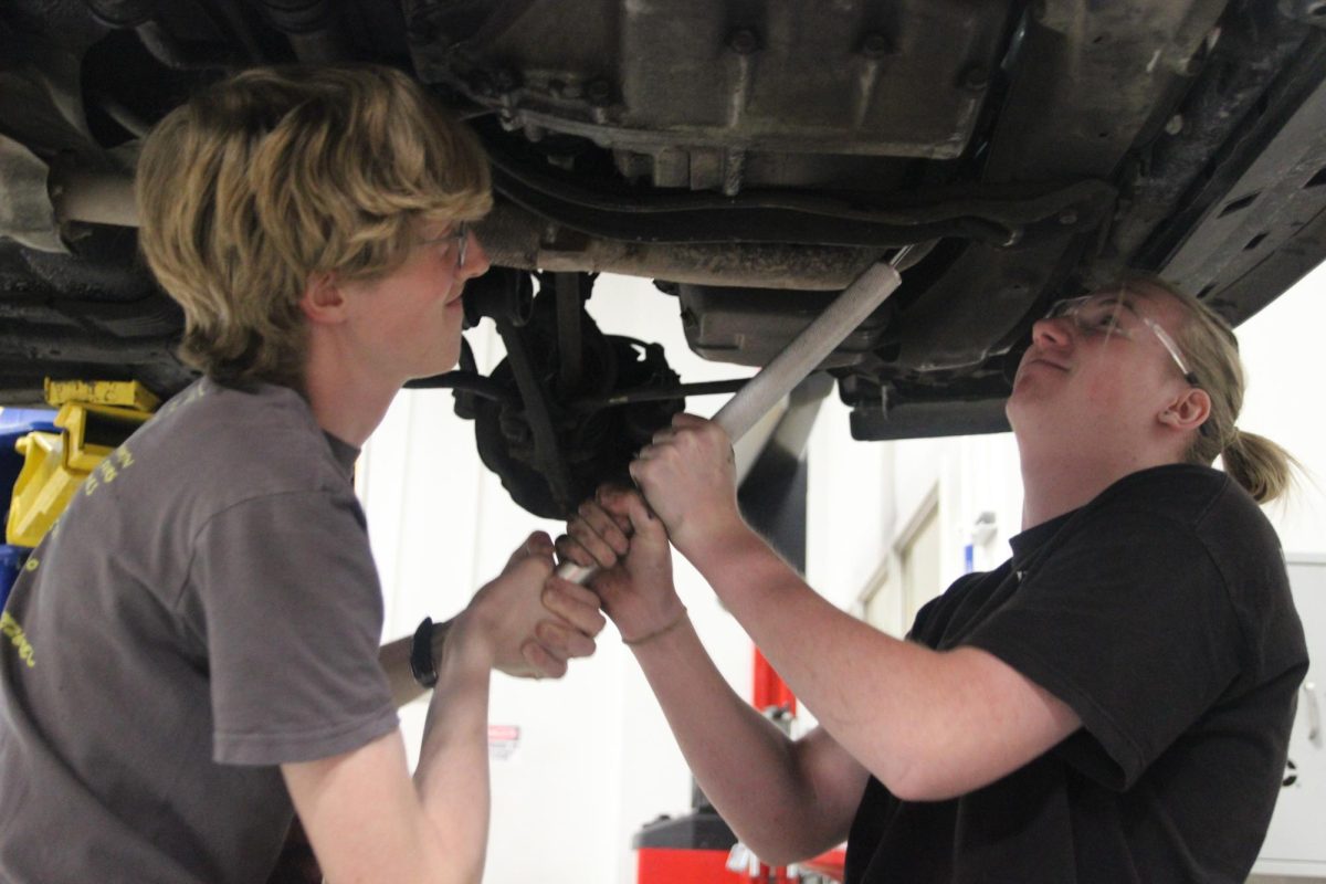 Inspecting the car’s underside, junior Drake Malcolm tries to pry out a brake component. While collaborating with another student, Malcolm attempted to direct his classmate to where the component is. “It’s pretty simple,” Malcolm said. “Of course, taking the rotor off is pretty simple. If it’s a drum brake system, it’s a little bit more complicated; you have to take apart a bunch of hydraulic systems, and other stuff, but overall brake jobs are relatively easy.”