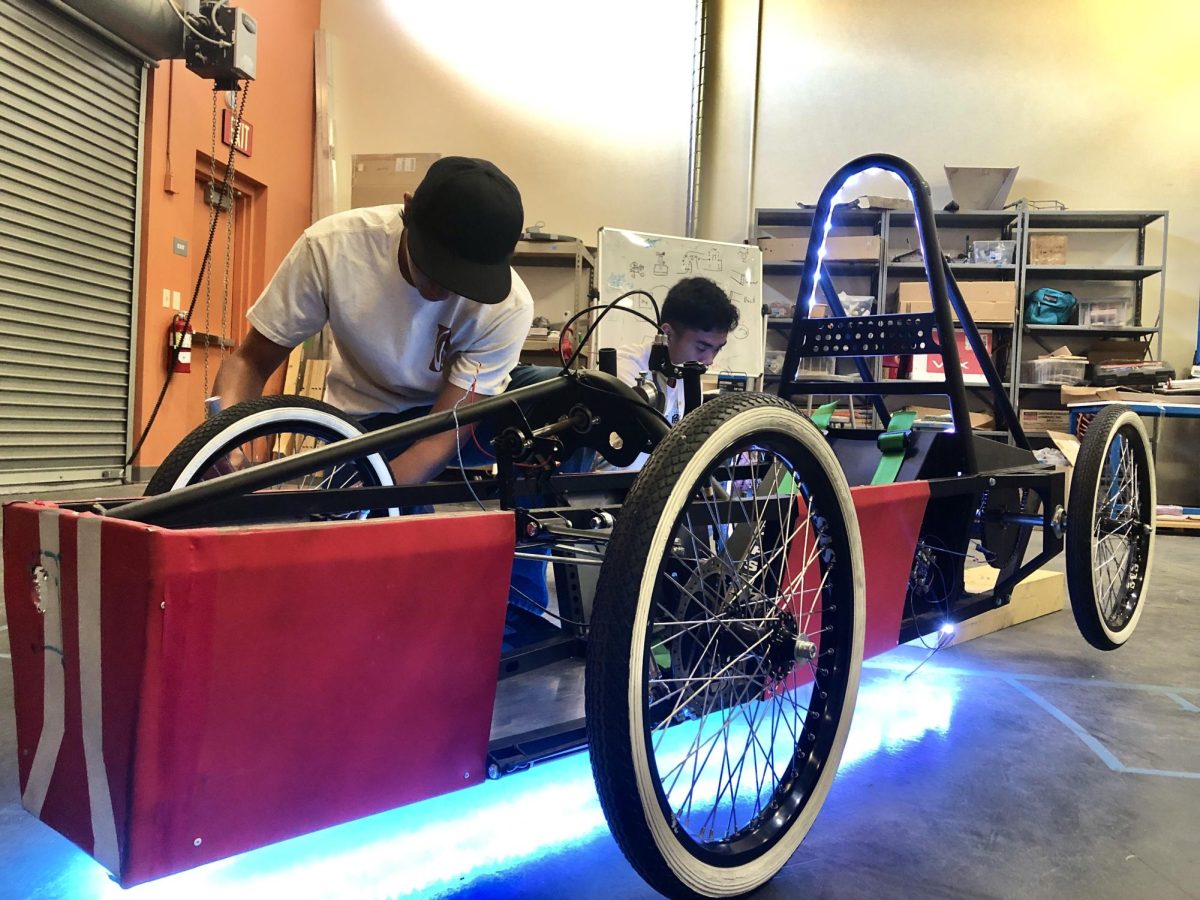 Inspecting the kart, sophomores Makoa Apao and Christian Reyes make some slight adjustments to the build. The project has been led by senior Connor Wiggins. “I really like the original framework of [the kart],” sophomore Makoa Apao said. “I feel like when they originally designed it, the kart was really well built, and I really appreciate the craftsmanship on it. [Through our work], we've implemented keyhole systems to restrict access to it. We've also implemented LEDs as an underglow.”