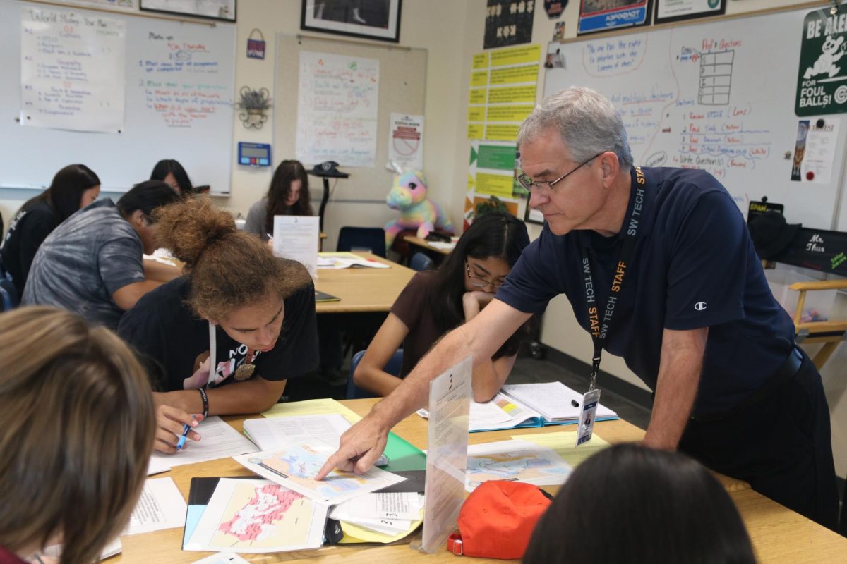  In his fifth period World History class, Thur works with his students individually, helping them as they sort through notes and assorted historical documents. “I’m always willing to try something new,” Thur said. “Some of my best ideas that I’ve received over the years are from students. This year I’m trying out stations for the first time and kids are rotating through and it’s working. Well, some things are [working], I’ve still got to work out the kinks with it. The kids change, why shouldn’t I change too?”
