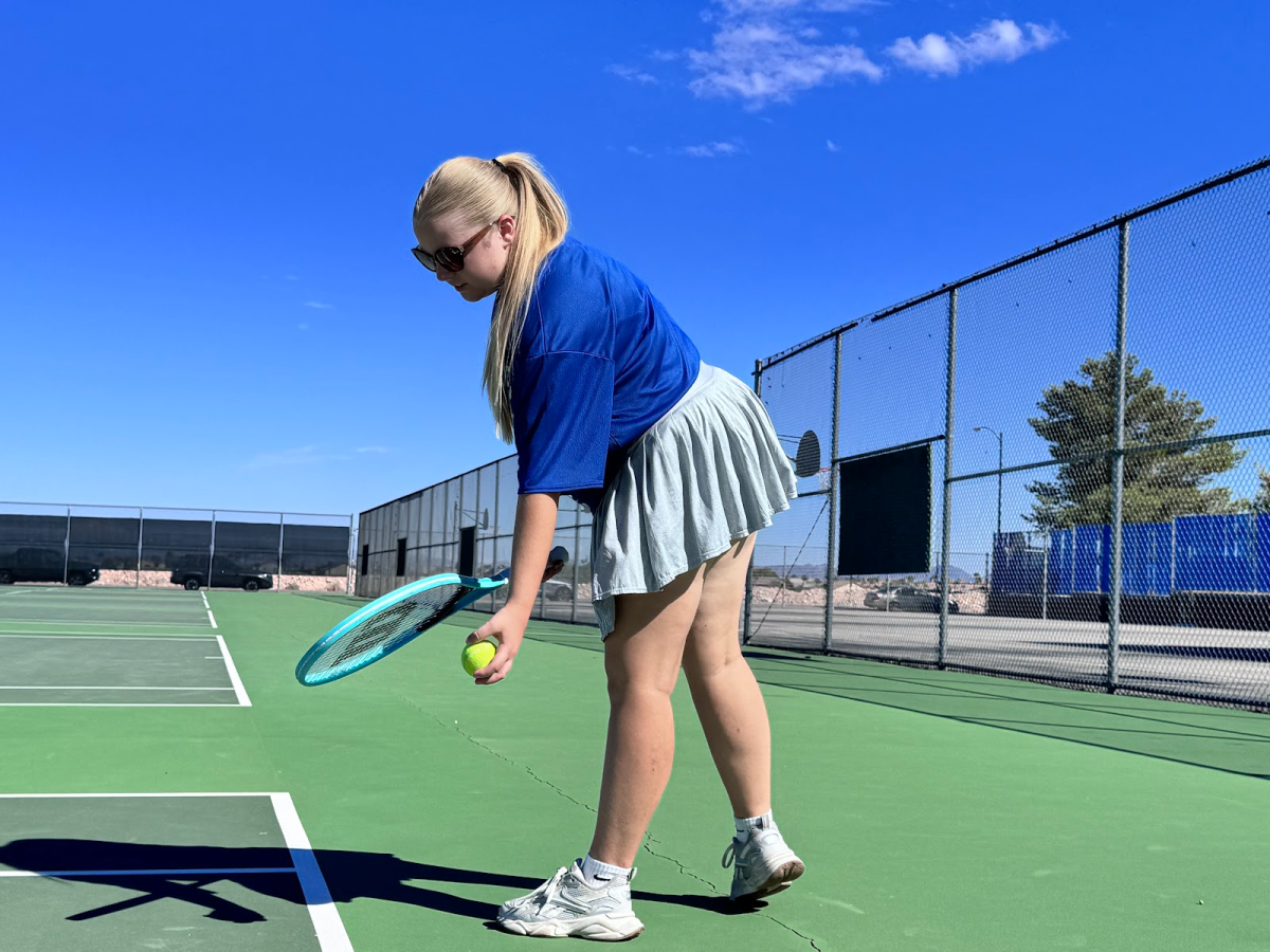 Swaying and preparing to toss the tennis ball, Dylan Grove practices serving. Grove had been training in preparation for her upcoming matches against Chaparral and Doral Red Rock. “[Both teams are] both very tough opponents, but I am ready for whatever gets thrown my way,” Grove said. 
