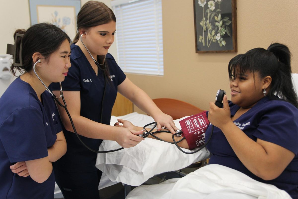 Placing the stethoscope bell over the brachial pulse, Nursing students find the artery and correctly measure the blood pressure of a practice patient. Students were divided into small groups to practice skills together. “I try to feel for the branchial artery each time I put on the cuff, [to make sure] I am putting the stethoscope on the right place [I check to ensure] my sound is correct,” senior Kelly Ngo said. “I also hold the stethoscope by the bell so I don’t hear too much interference and can focus on hearing the blood pressure.”
