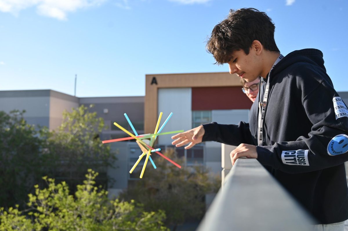 Reaching over the rail, Aiden Filimon drops his straw contraption during a physics experiment.