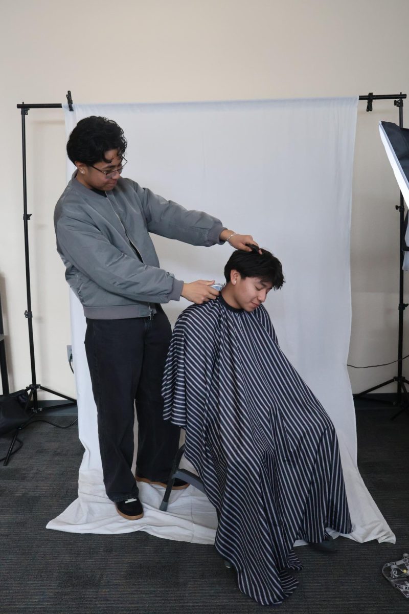 Junior Jayden Pascual poses with student model junior Alejandro Merino. As part of a photoshoot, Pascual demonstrates his customer service on Merino. "I just talk to them, just to get to know them," Pascual said. "I think that's the fun part about cutting hair, you get to meet a lot of people and get to improve communication skills and know more about them."